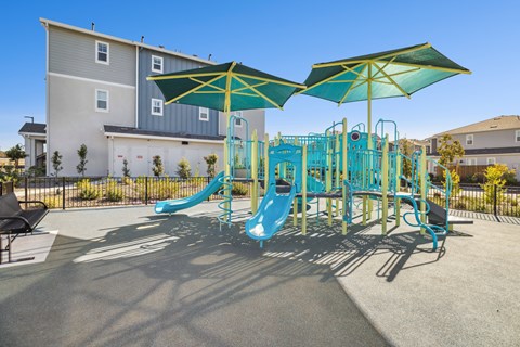 A playground with a blue slide and green umbrellas.