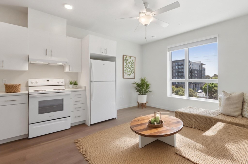 A modern kitchen with white appliances and a wooden coffee table.