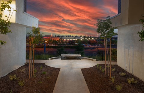 a park bench in the middle of a courtyard with a sunset in the background