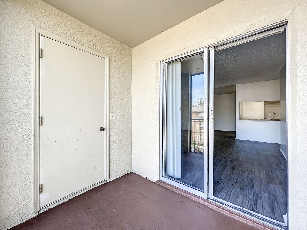 a bedroom with a sliding glass door and a kitchen in the background