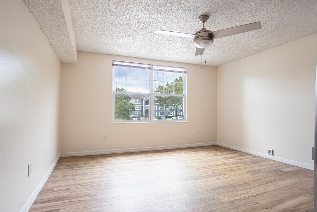 an empty living room with a ceiling fan and a large window
