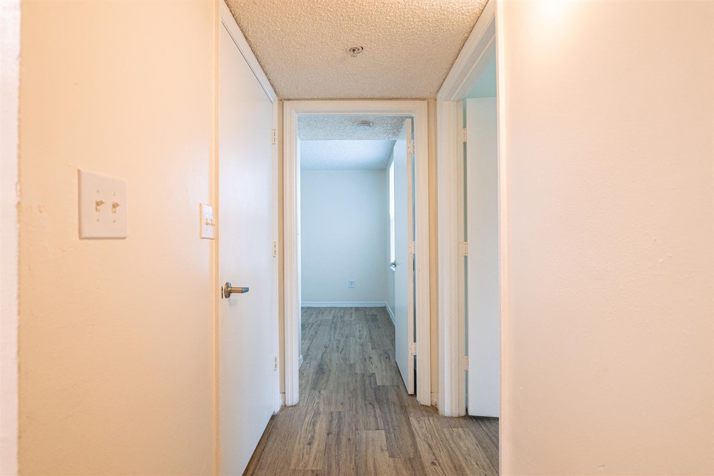 an empty hallway with wood floors and a white door