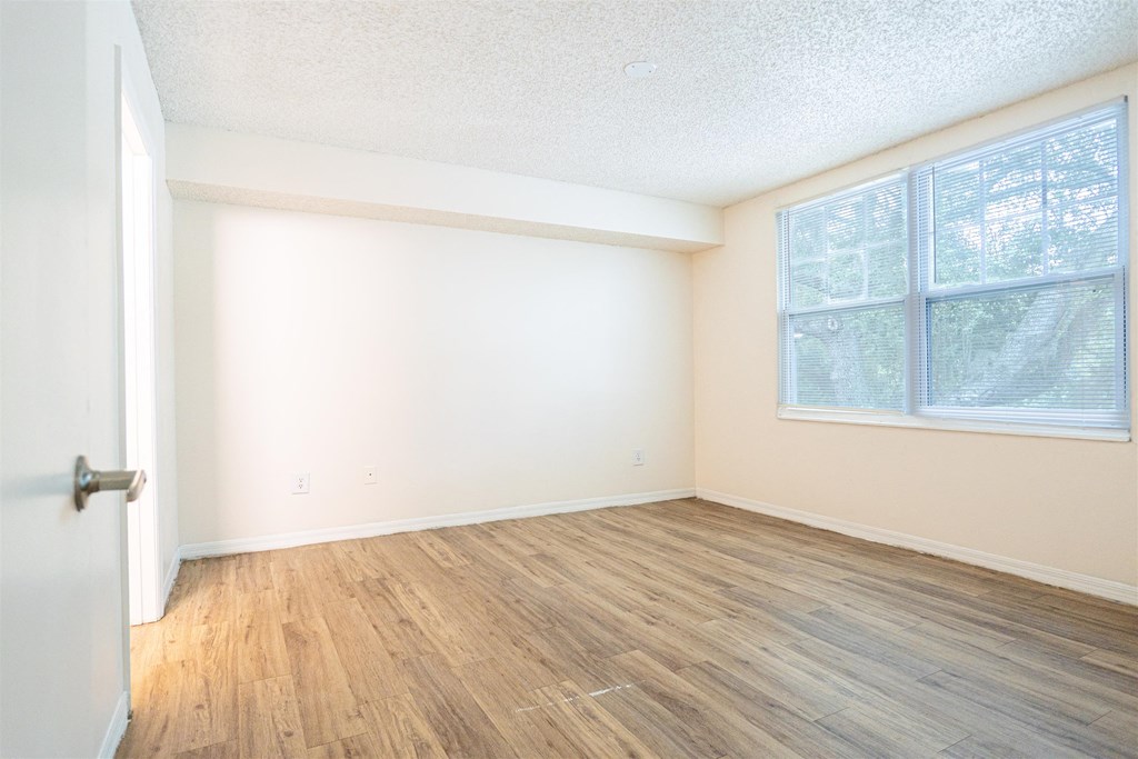an empty room with wood flooring and a large window