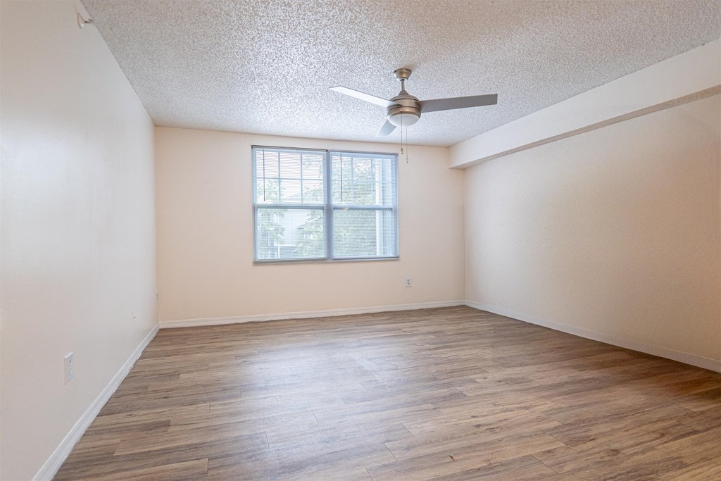 an empty living room with a ceiling fan and a window