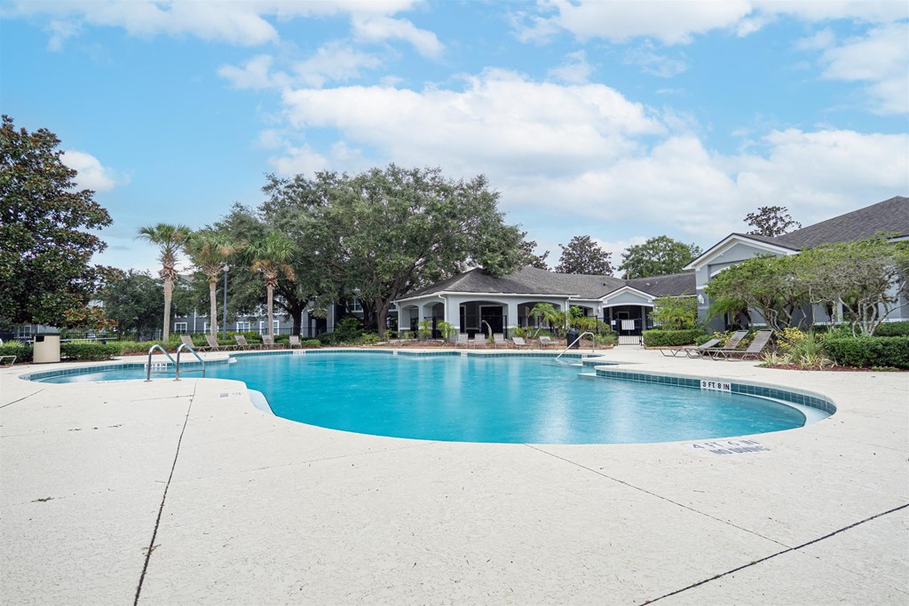a large swimming pool with a house in the background