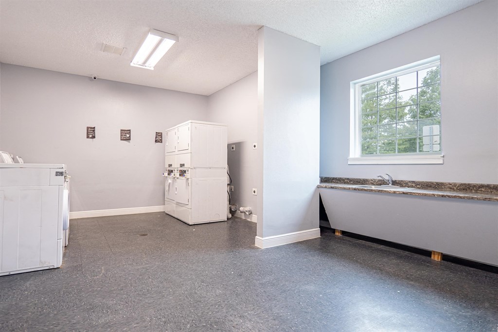 an empty room with a sink and a tub and a window