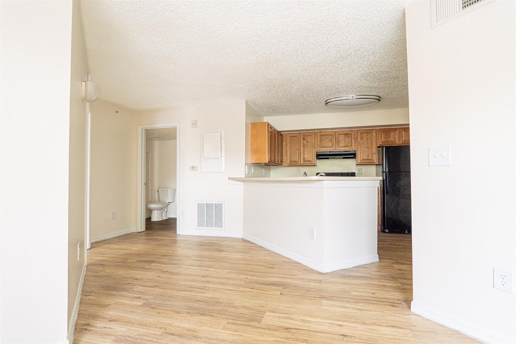 an empty living room and kitchen with wood floors