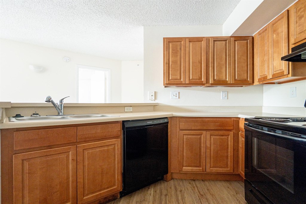 an empty kitchen with wooden cabinets and black appliances
