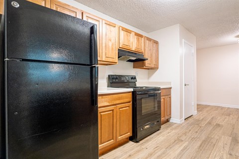 a kitchen with a black refrigerator and wooden cabinets