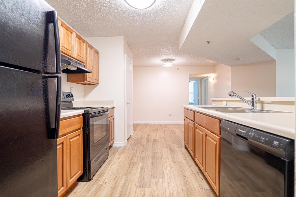 a kitchen with wooden cabinets and a black refrigerator and dishwasher