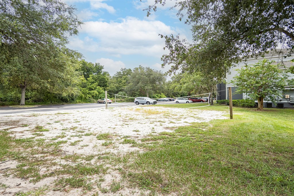 a volleyball court in a park with cars parked in a parking lot