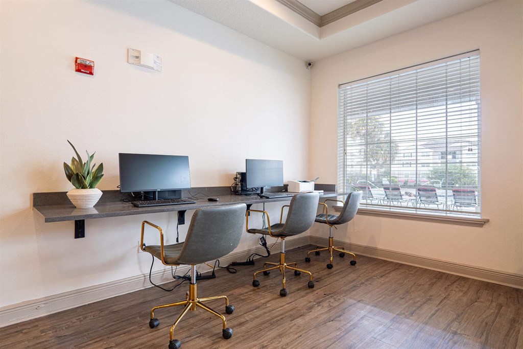 a home office with a desk with two computers and a window