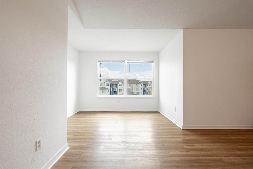 an empty room with wood floors and a window