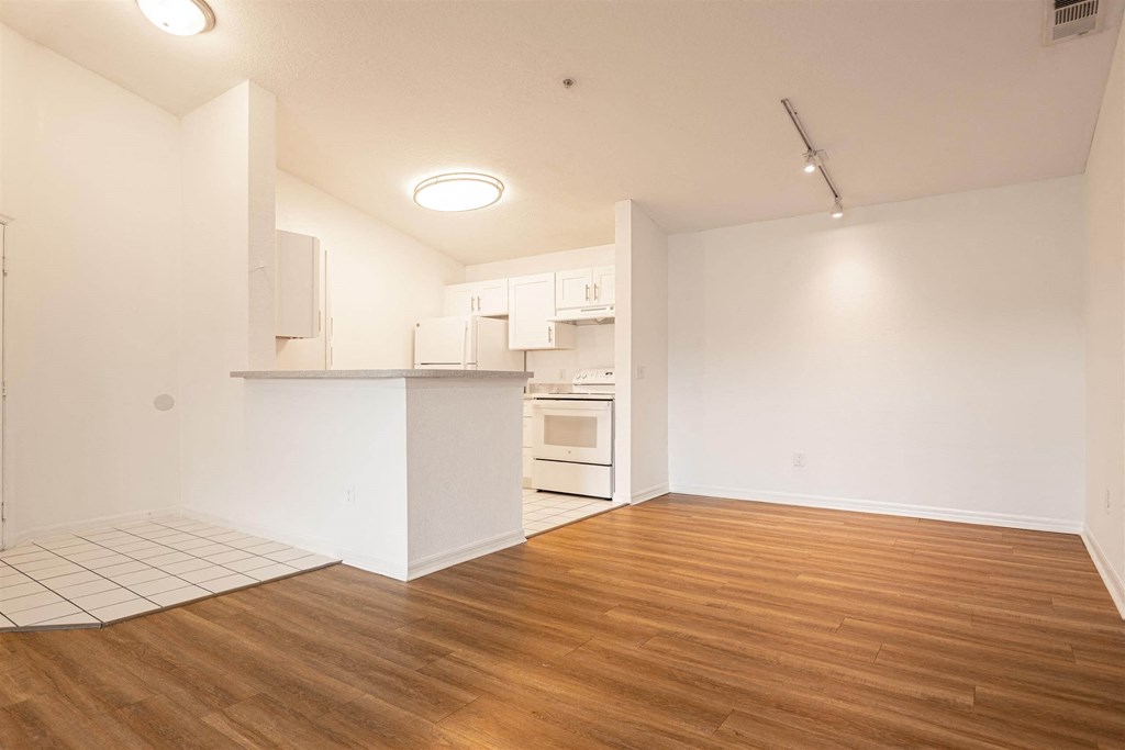 an empty living room and kitchen with white walls and wood floors