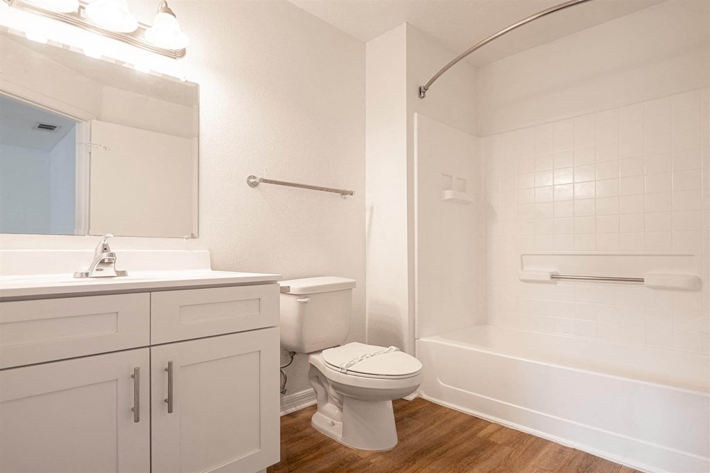 a white bathroom with a toilet and a bath tub
