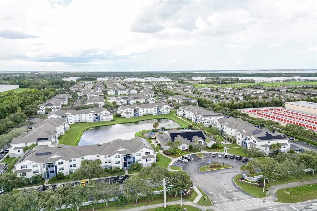 an aerial view of an apartment complex with a pond and parking lot