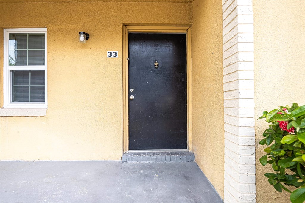 a yellow house with a black door and a porch