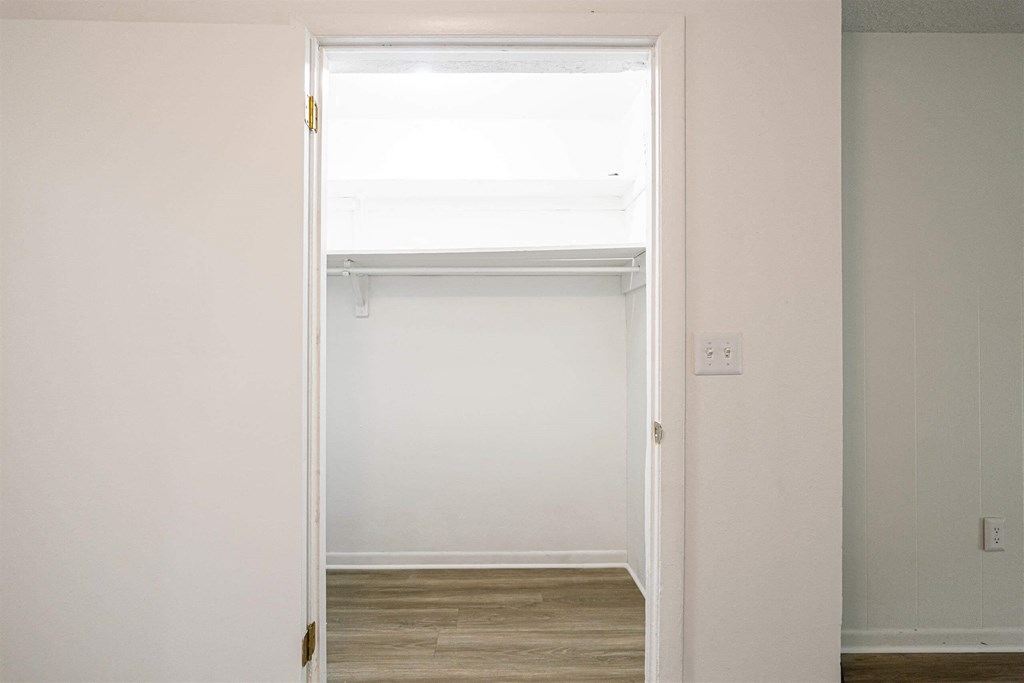 an empty room with a door open to a closet