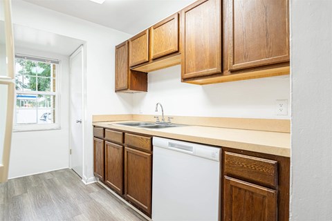 a small kitchen with wooden cabinets and a white dishwasher
