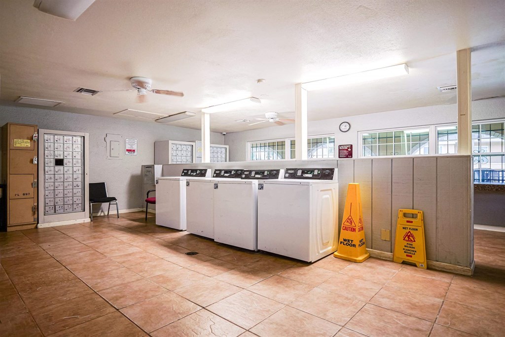a laundry room with four washing machines and a yellow caution sign
