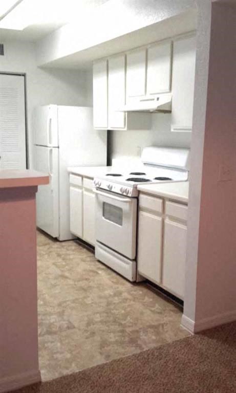 an empty kitchen with white appliances and white cabinets