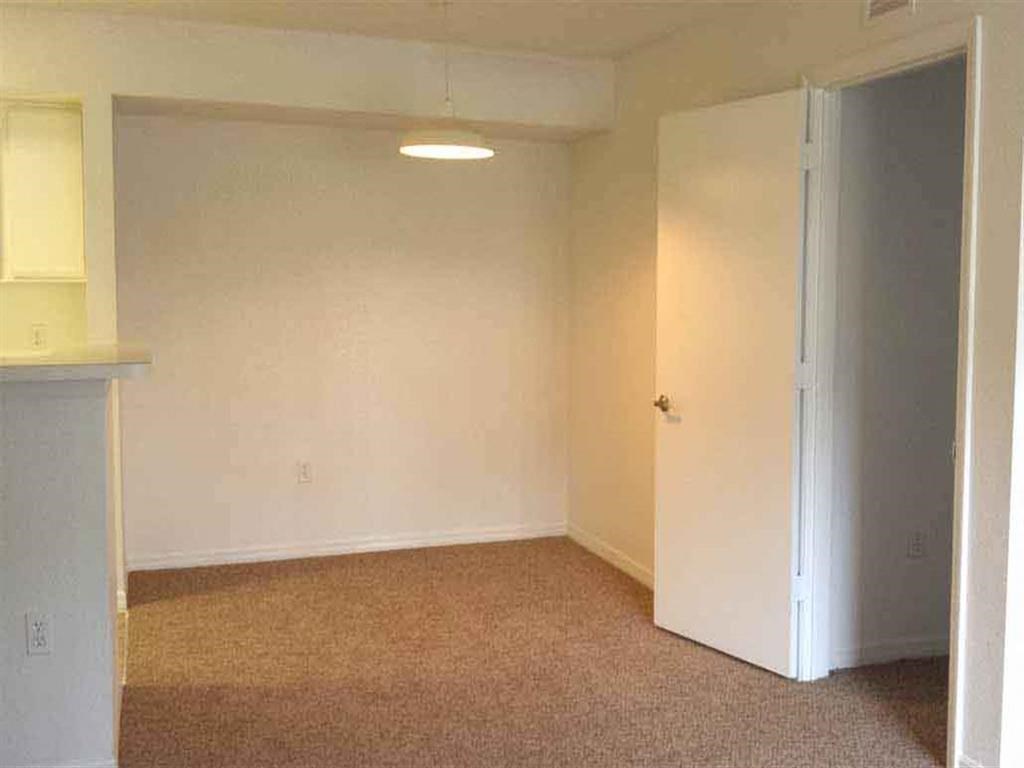 an empty living room with a door open to a bedroom