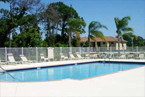 a swimming pool with chairs and a white fence around it