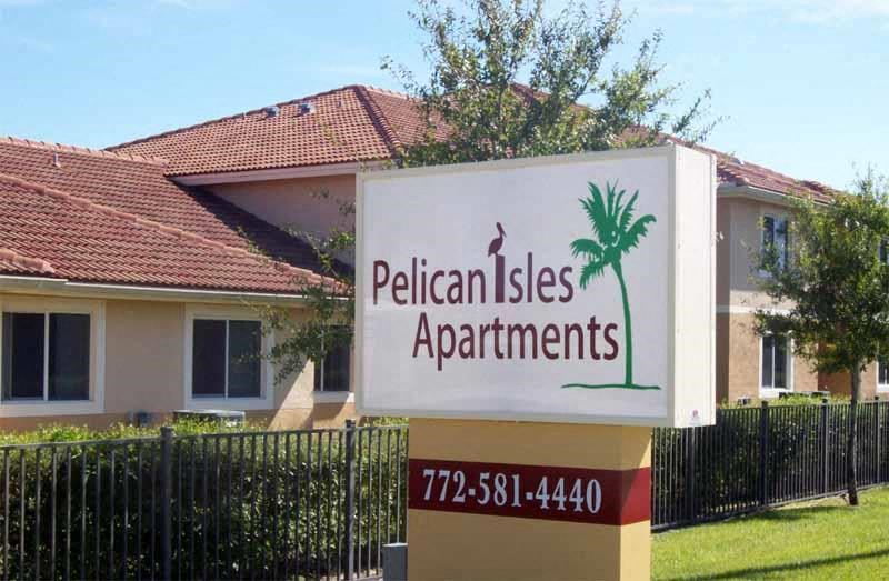 a sign for pelican estates apartments in front of a house