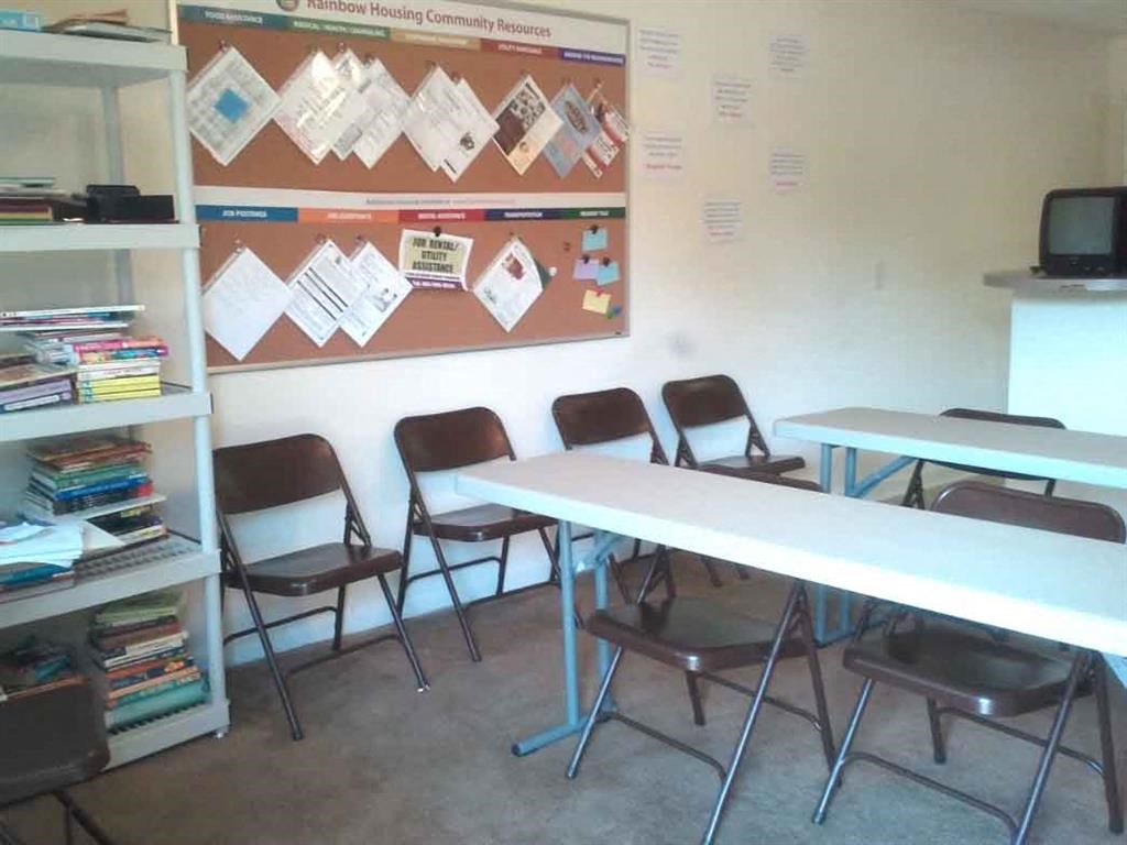 a classroom with desks and chairs and a bulletin board on the wall