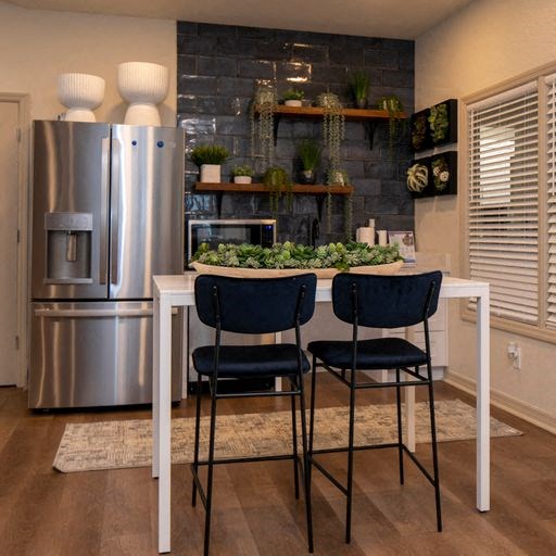 a kitchen with a table and chairs and a stainless steel refrigerator