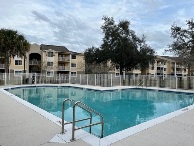 a pool with a fence around it in front of an apartment building