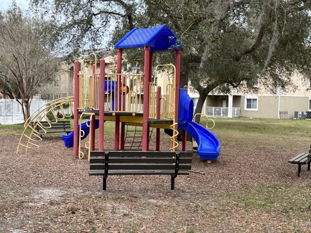 a playground with a bench and slides in a park