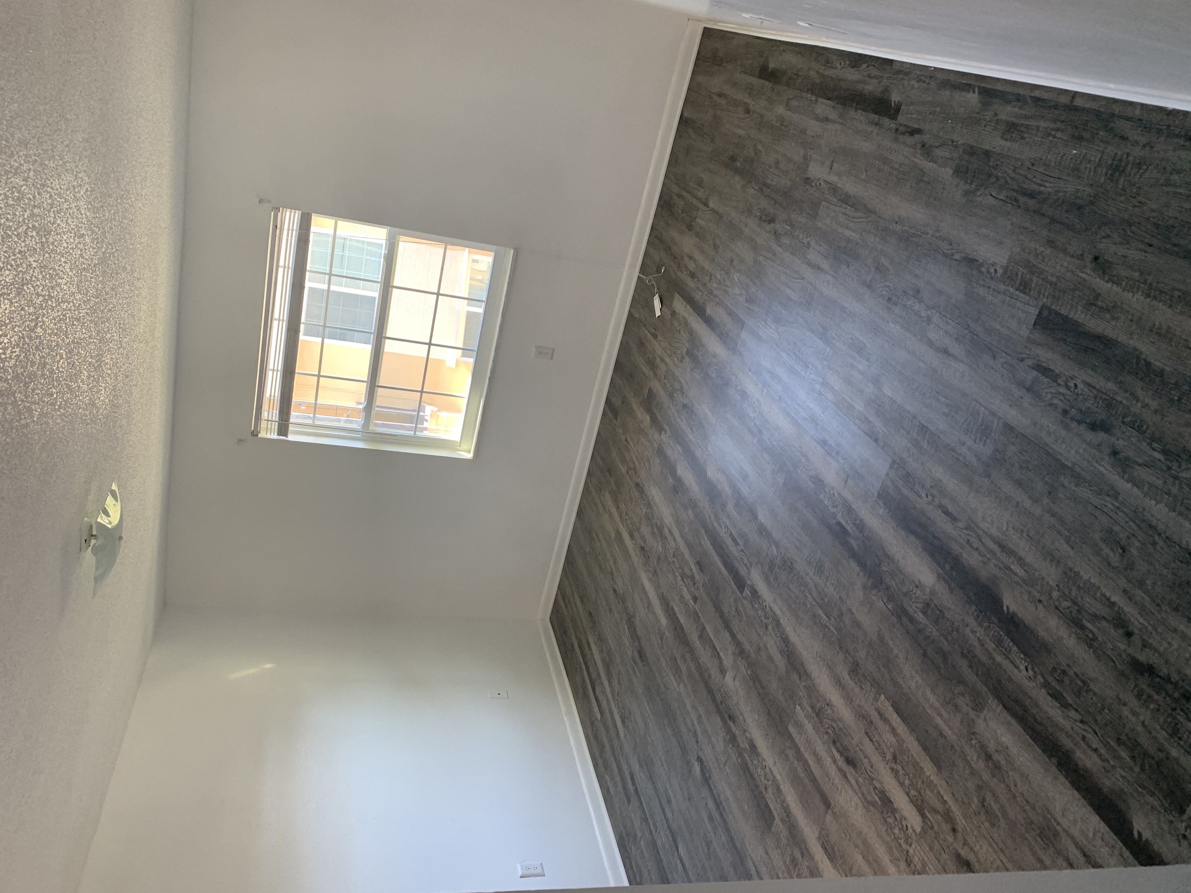 an empty room with a window and a wall with a wooden floor