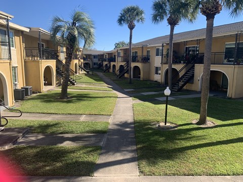 a row of apartment buildings with palm trees in the grass