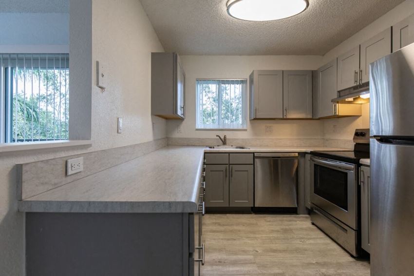 a kitchen with gray cabinets and stainless steel appliances