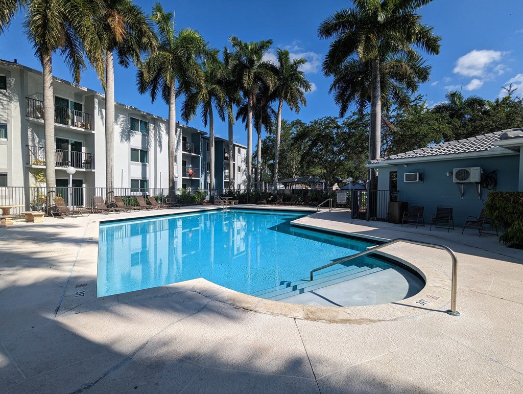 a swimming pool with palm trees in front of an apartment building