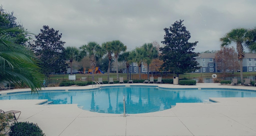 an empty swimming pool with trees and buildings in the background