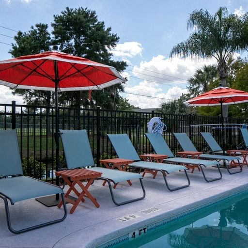 a swimming pool with lawn chairs and umbrellas