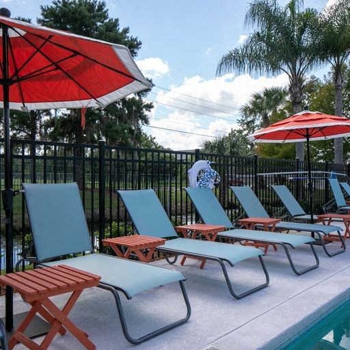 a group of lawn chairs and umbrellas on a pool