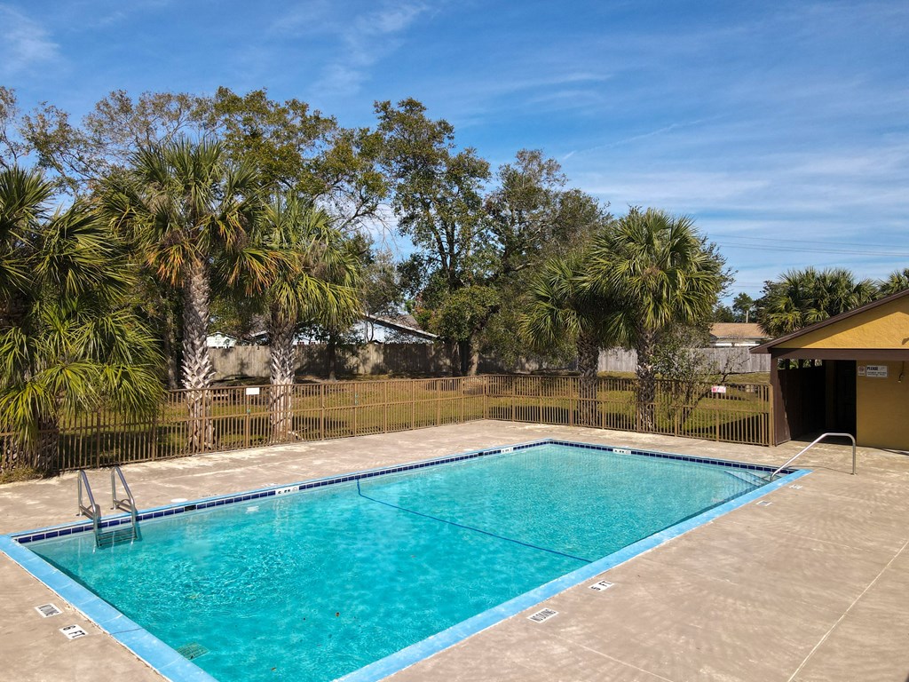 a swimming pool with a fence and palm trees in the background