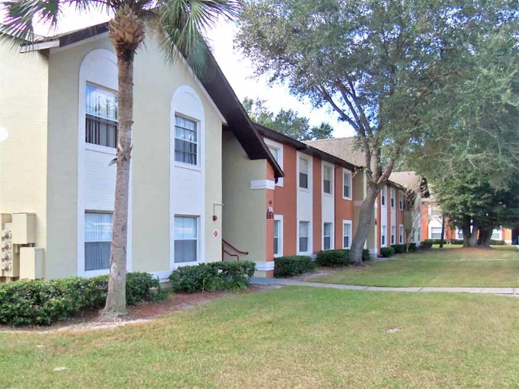 a row of apartment buildings with grass and trees
