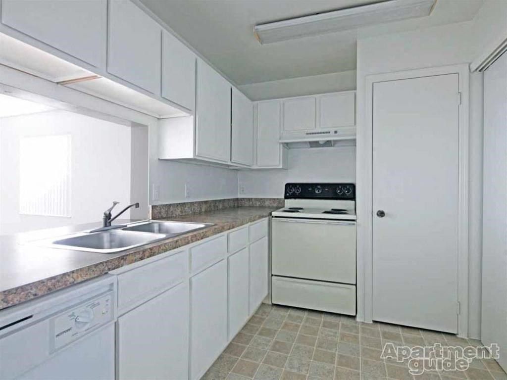 a kitchen with white cabinets and a sink and a stove