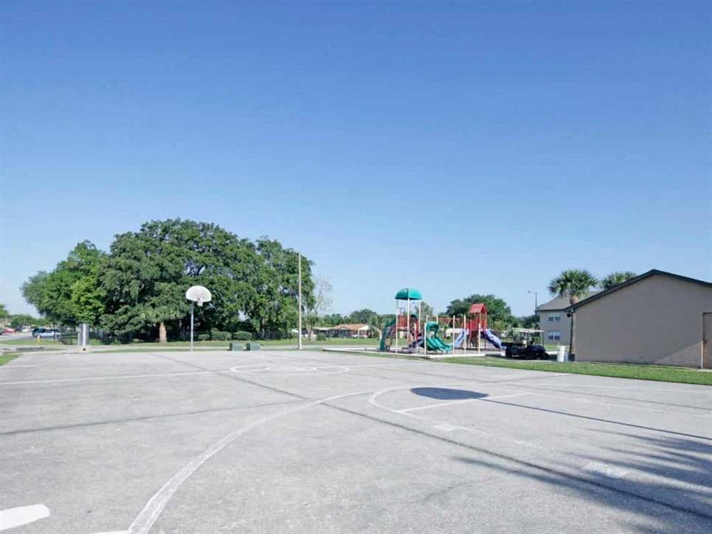an empty parking lot with a playground in the background