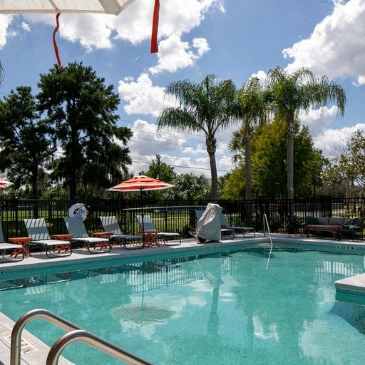 a swimming pool with chairs and an umbrella