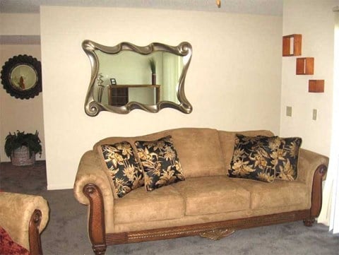 a living room with a couch and a mirror on the wall