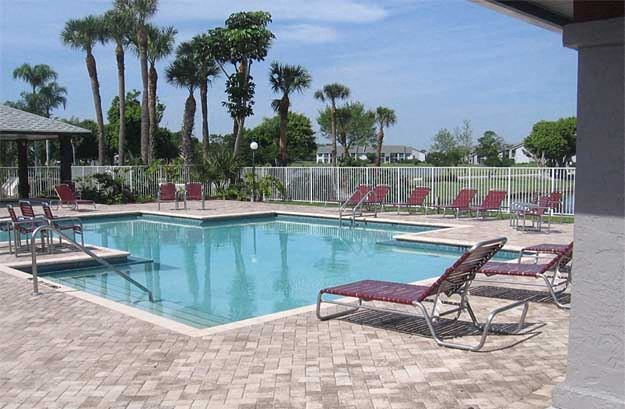 a swimming pool with red chairs and trees