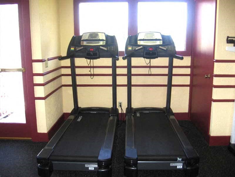 two treadmills in a room with two windows