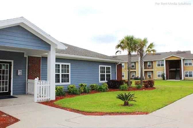 a blue house with a lawn and palm trees in front of it