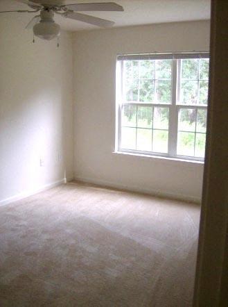 an empty bedroom with a window and a ceiling fan