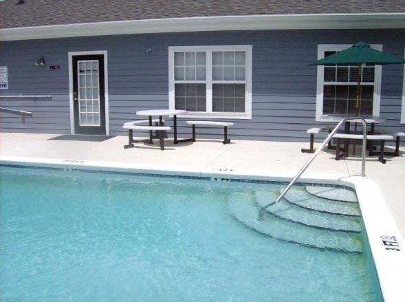 a swimming pool in front of a blue house